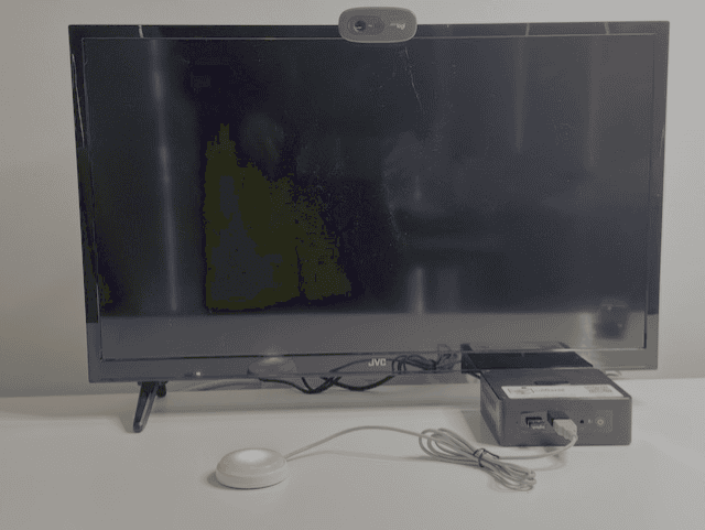 CallGenie device attached to television with the Do Not Disturb button activated.  The button has ared light on the television screen is black turned off.